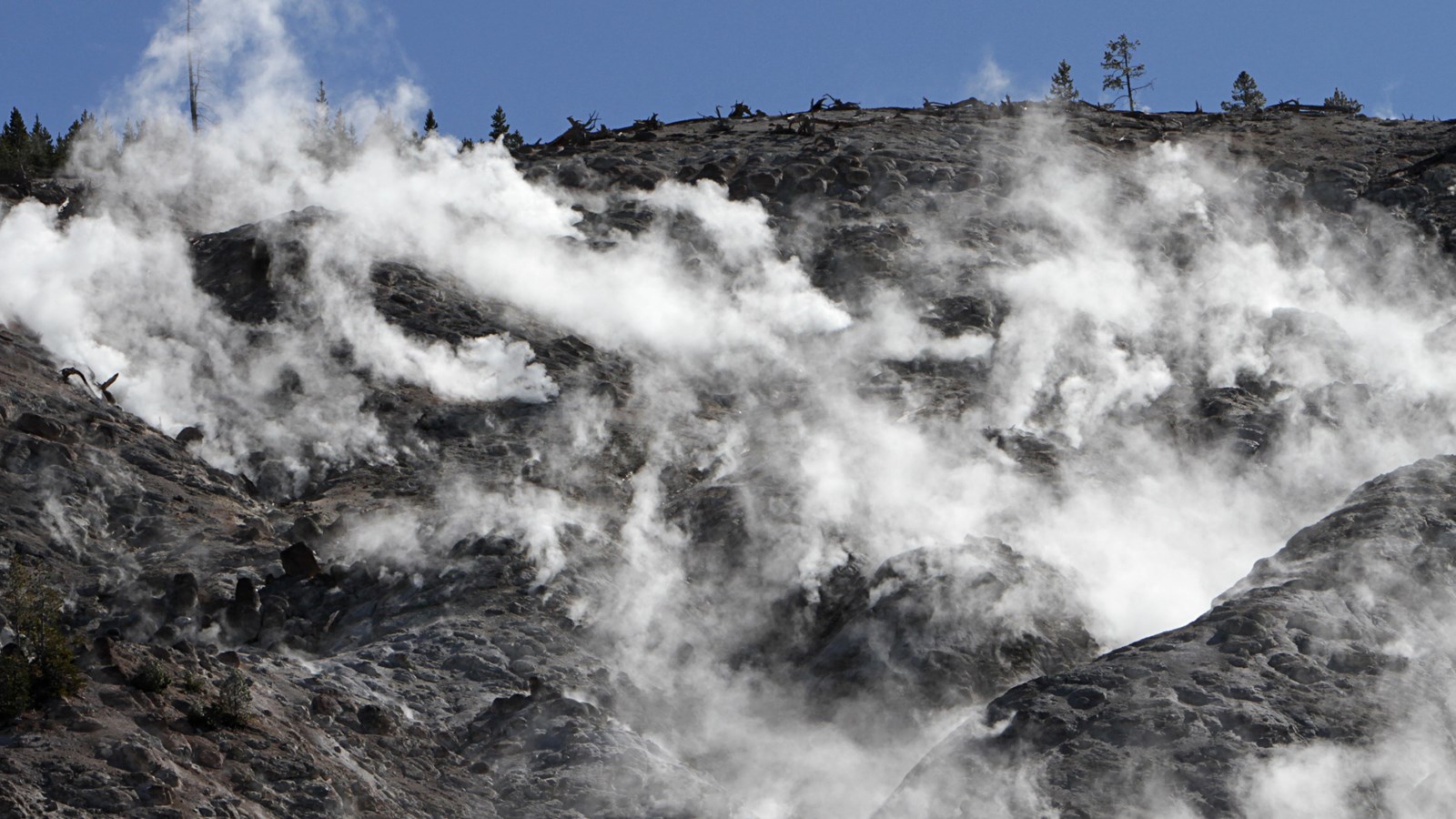 Steam rises from a steep, barren mountainside.