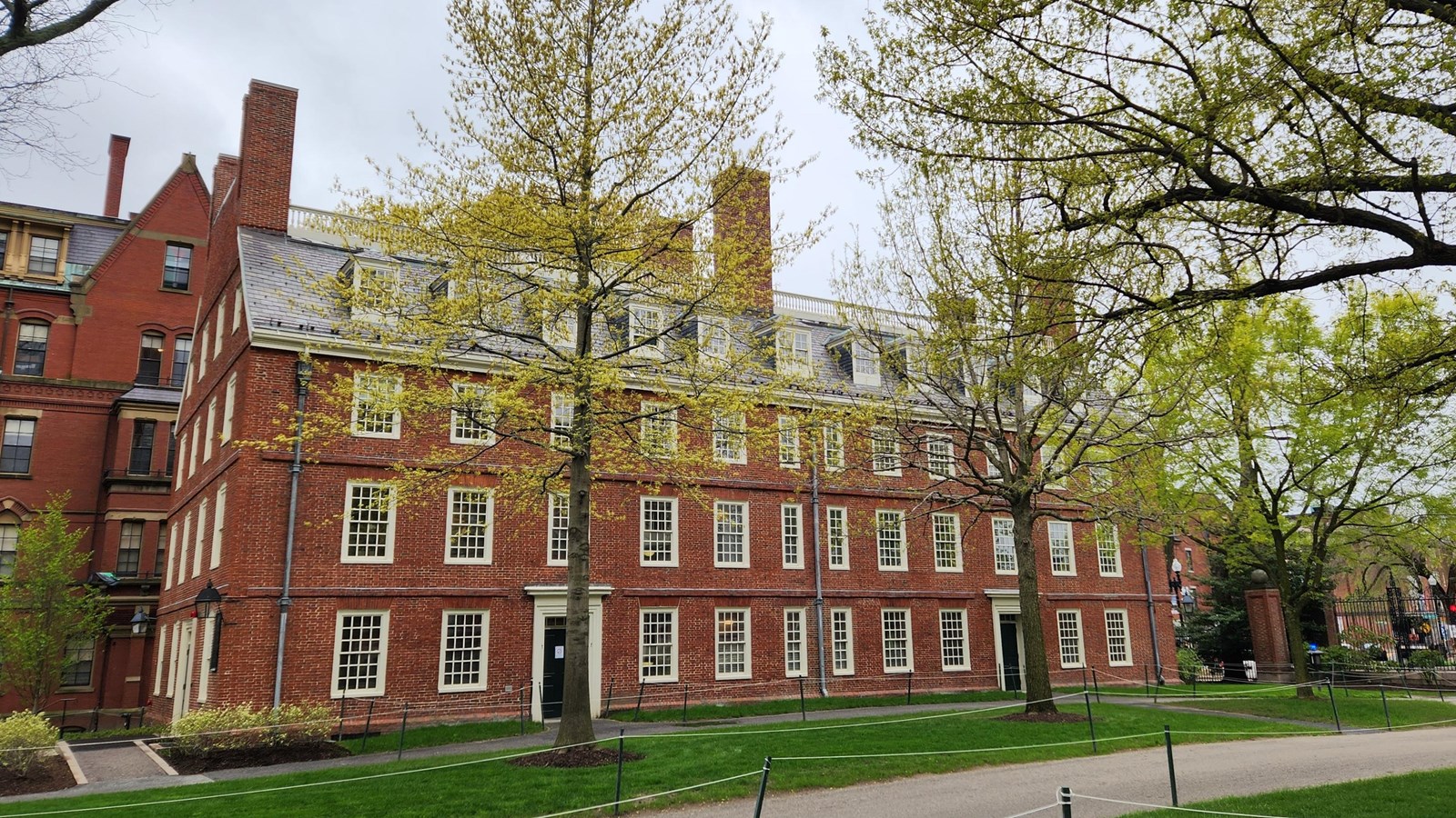 Large four-story brick building with six chimneys and 12 columns of windows and doors.