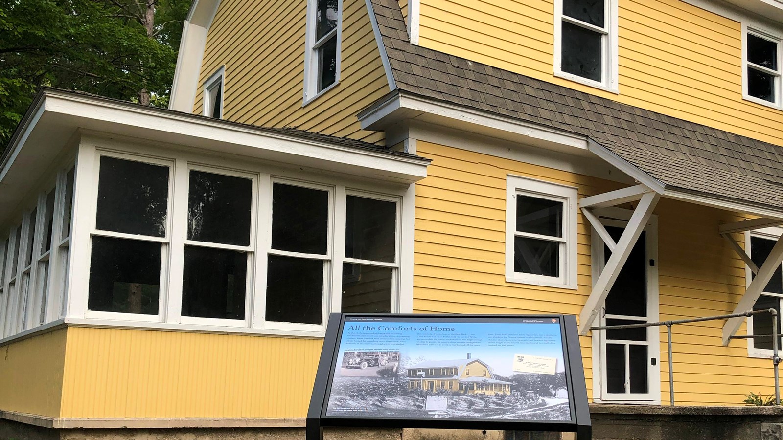 An informational sign stands in front of a yellow 
