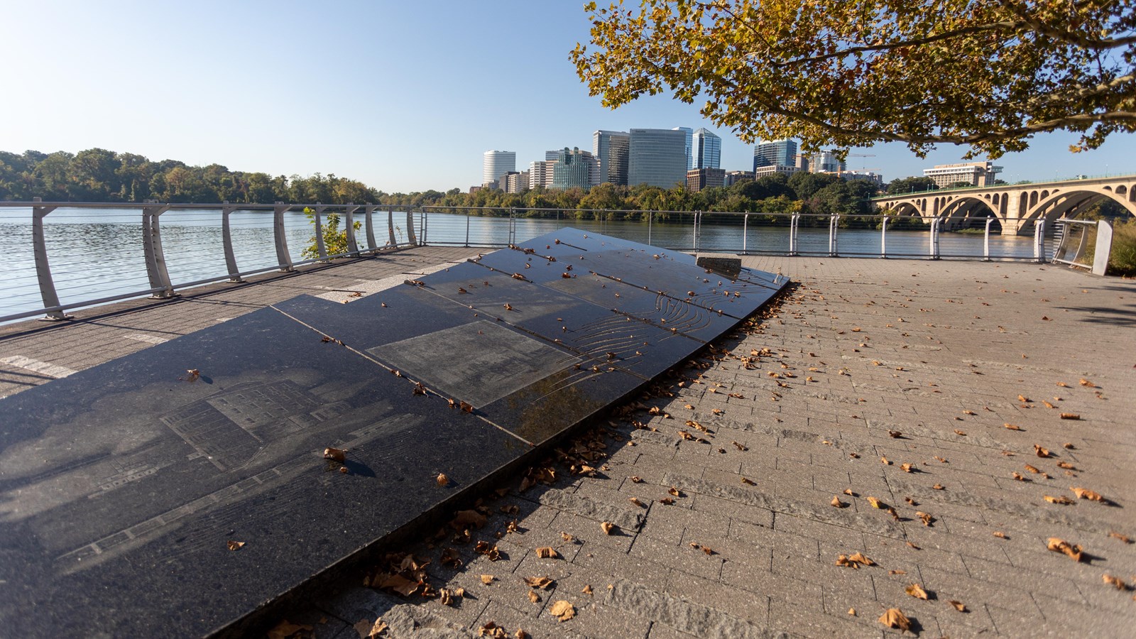 An angled stone marker with etchings by the water.
