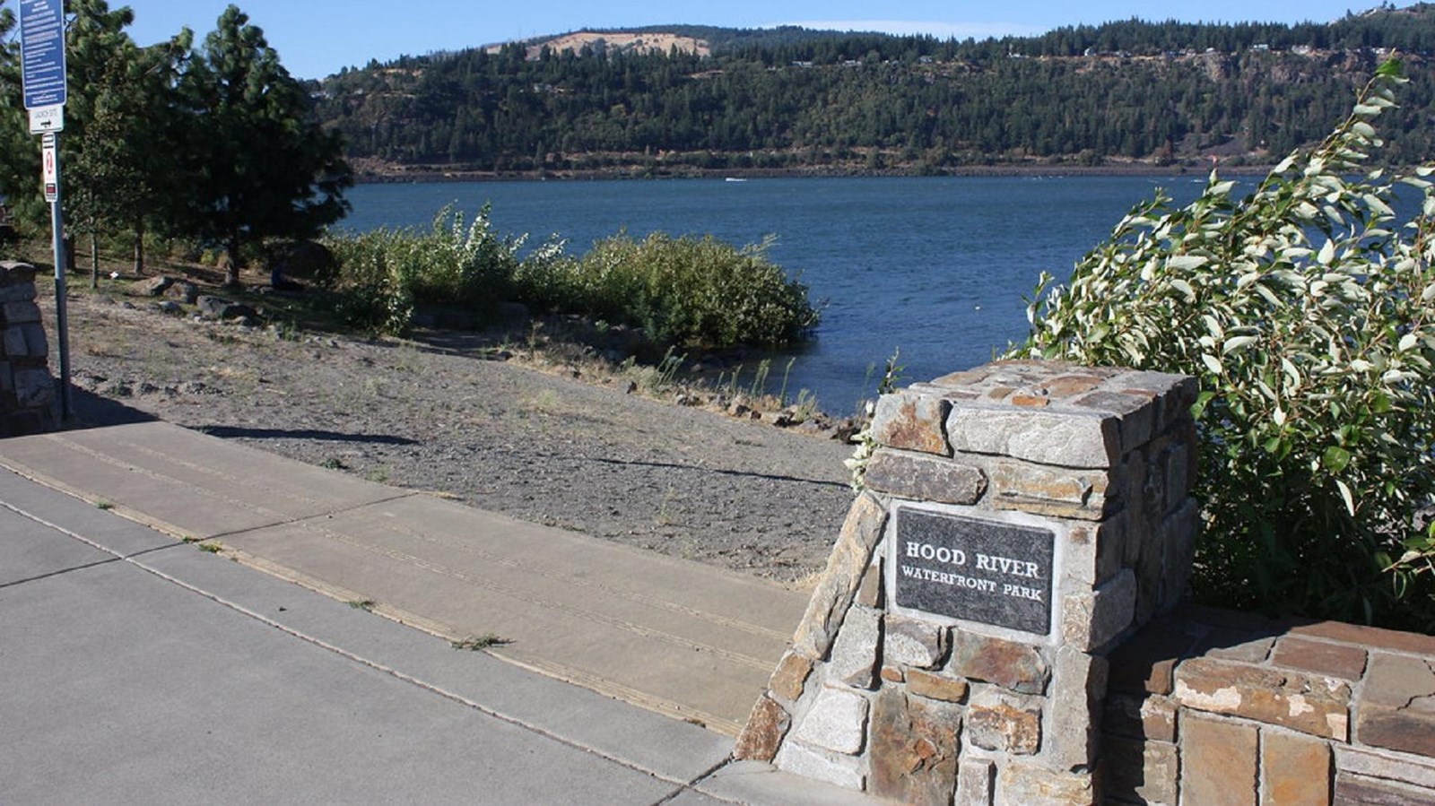 A sandy slope leads from a paved area to the water.