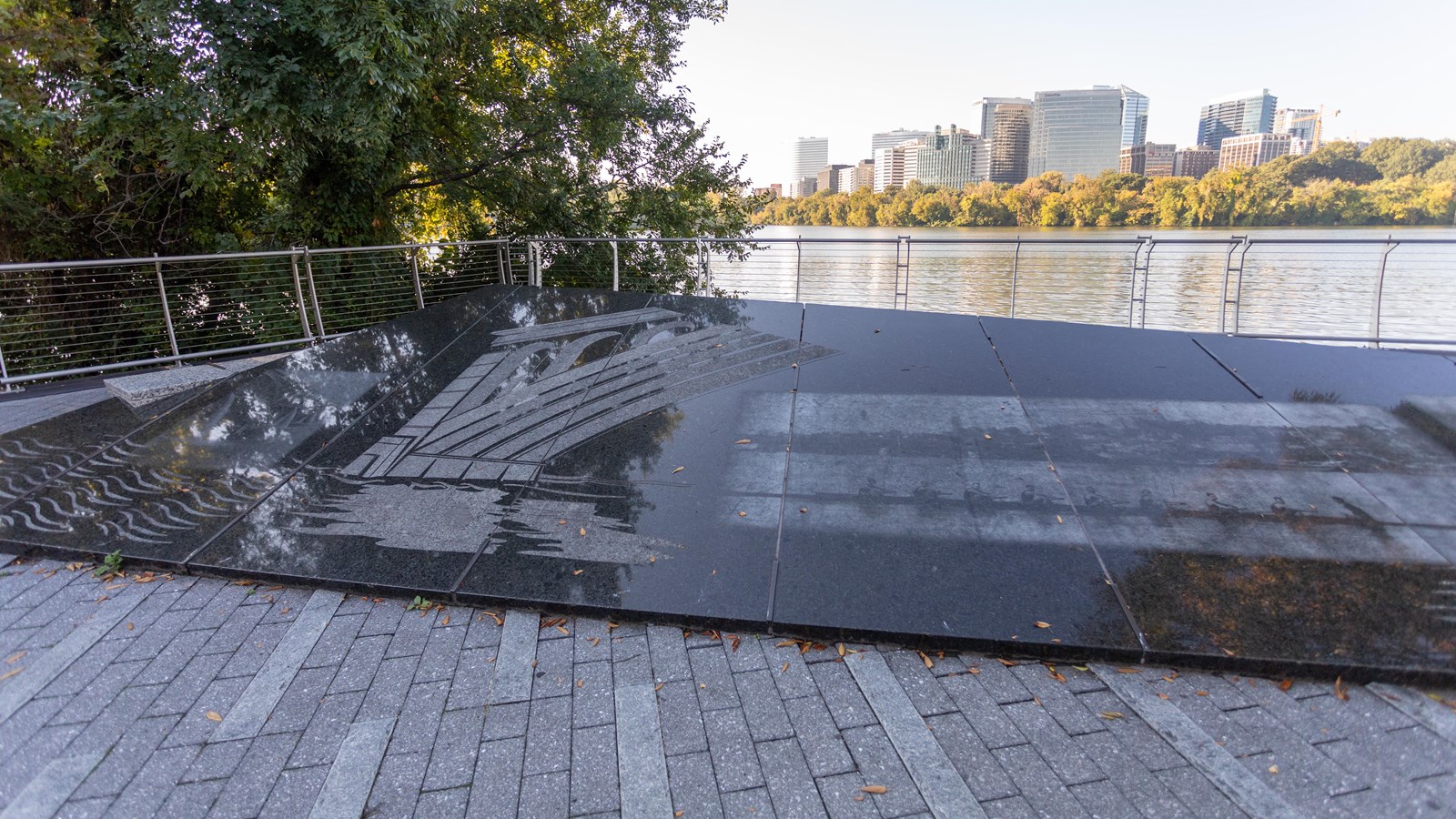 An angled stone marker with etchings by the water.