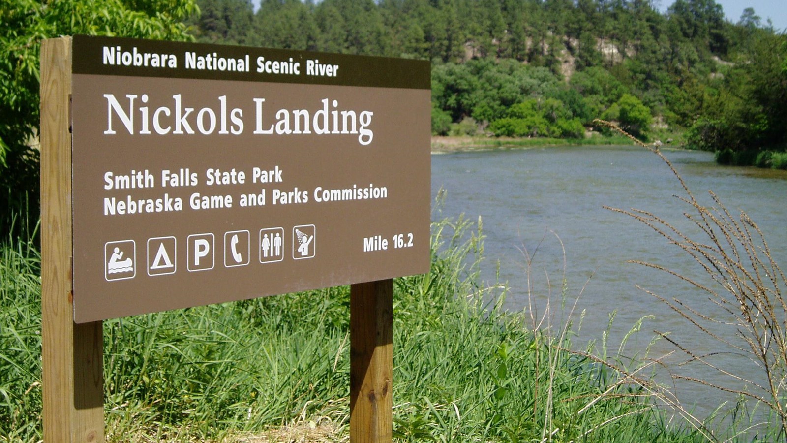 A brown sign on a river bank.