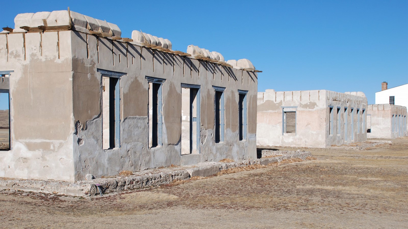 Three lime-grout concrete buildings in a row missing roofs, windows, and doors.