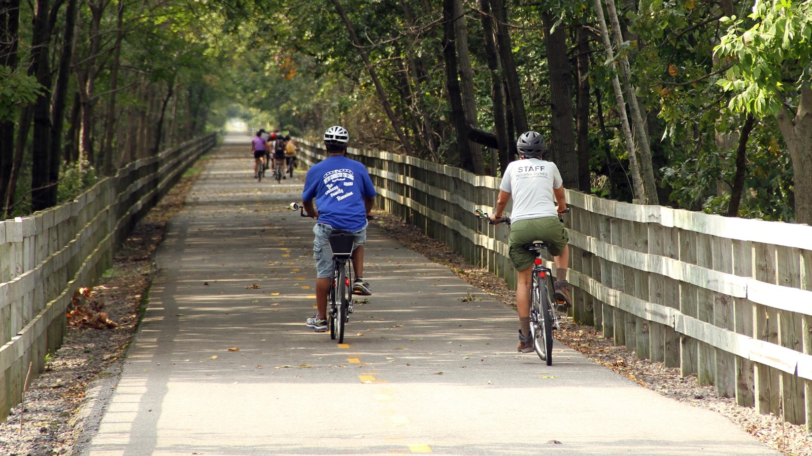 Ranger and visitors ride down the wide paved bike path.