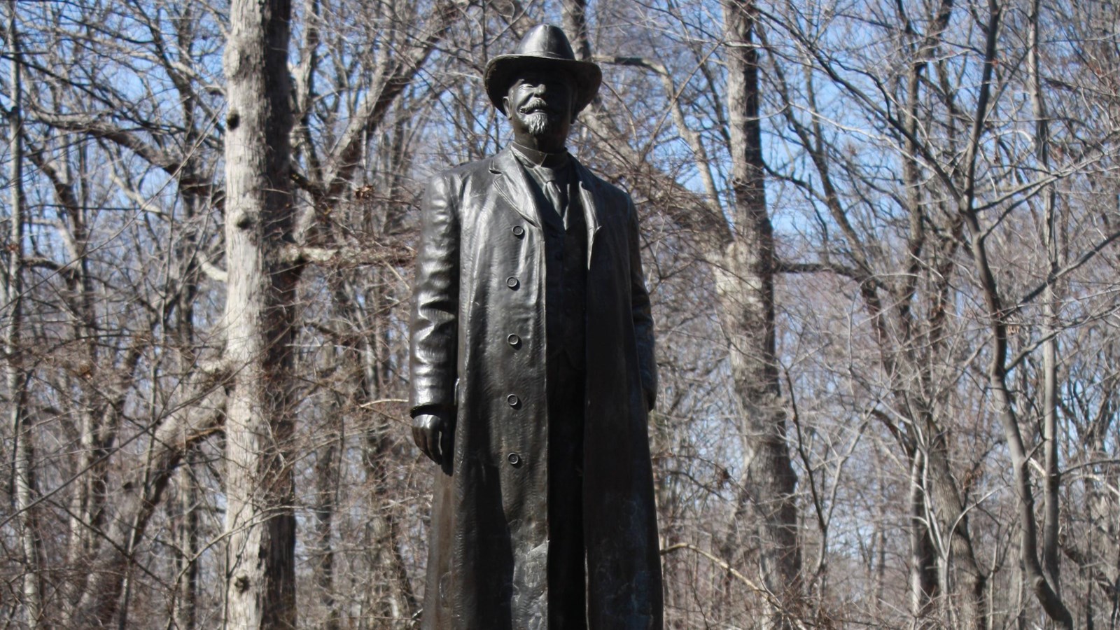Atop a boulder stands the statue of Joseph Morehead. Dressed in a long coat wearing a wide brim hat.