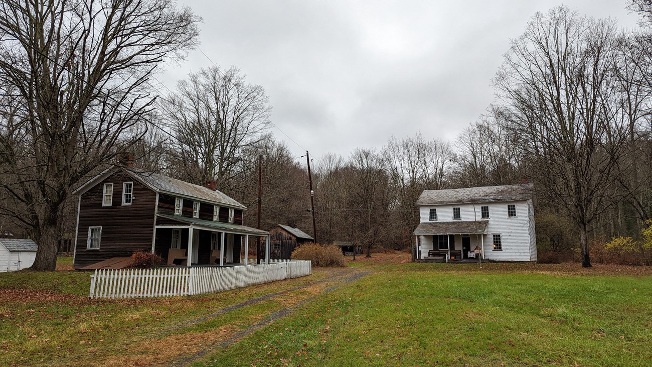 A brown inn with a white fence on the left. A white two-story general store building on the right.