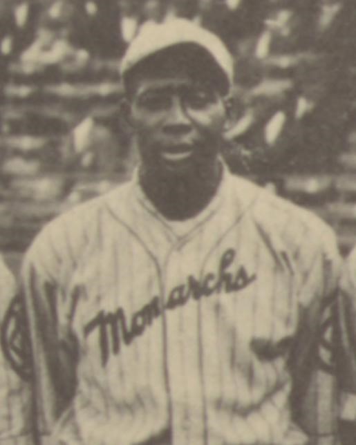 African American man stands in front of viewer wearing baseball uniform of the 1920s