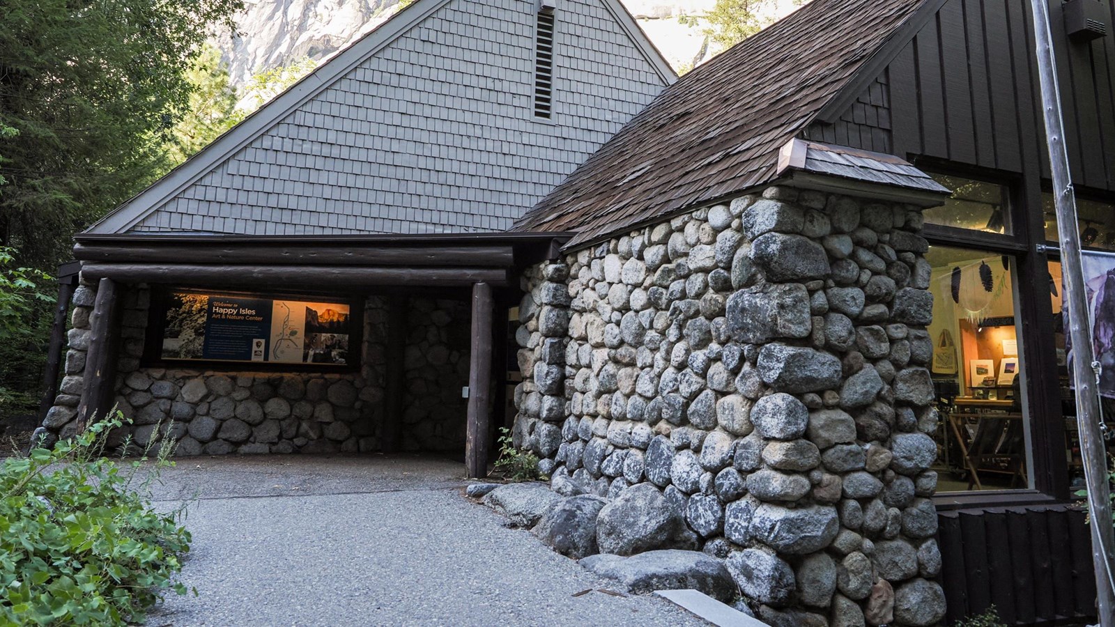 A single story building with a steeply pitched roof and river rock exterior walls