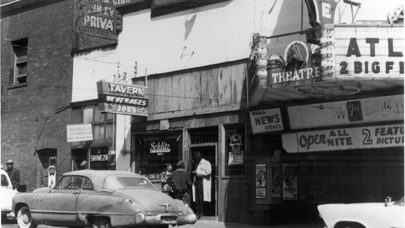 Mid-20th century urban scene, featuring a hotel, tavern, and theater.