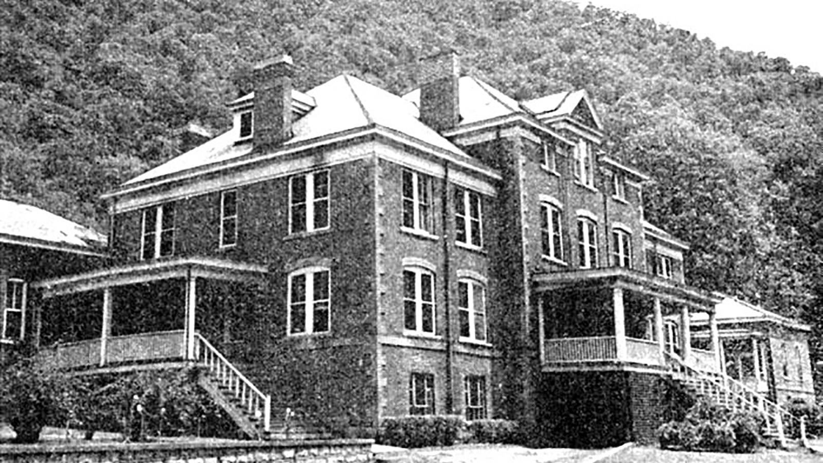 A historic black and white photo of a large, multi-story, old brick building