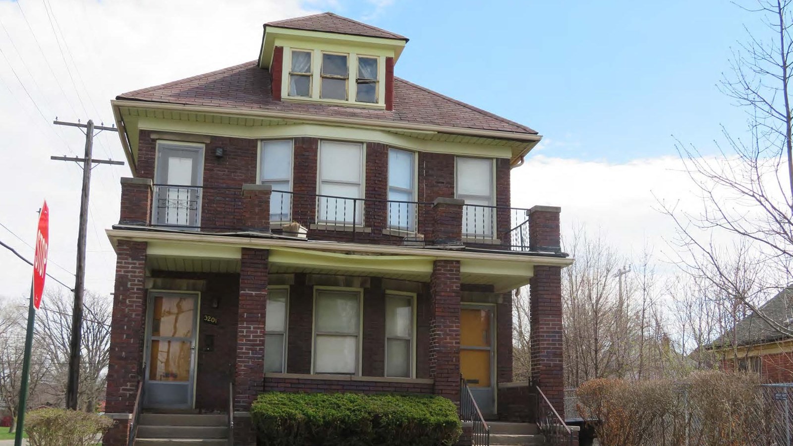 A two-and-one-half story Craftsman style brick building with asphalt shingles, with a porch