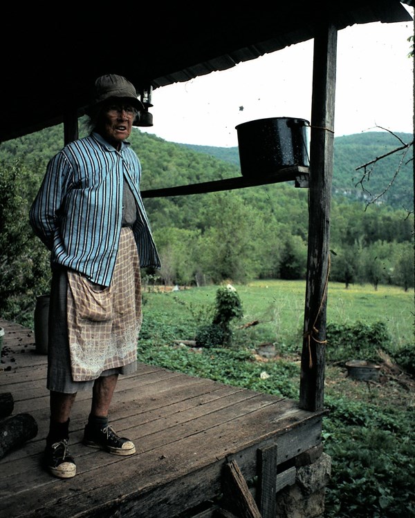 Granny Henderson stands on the front porch of her cabin