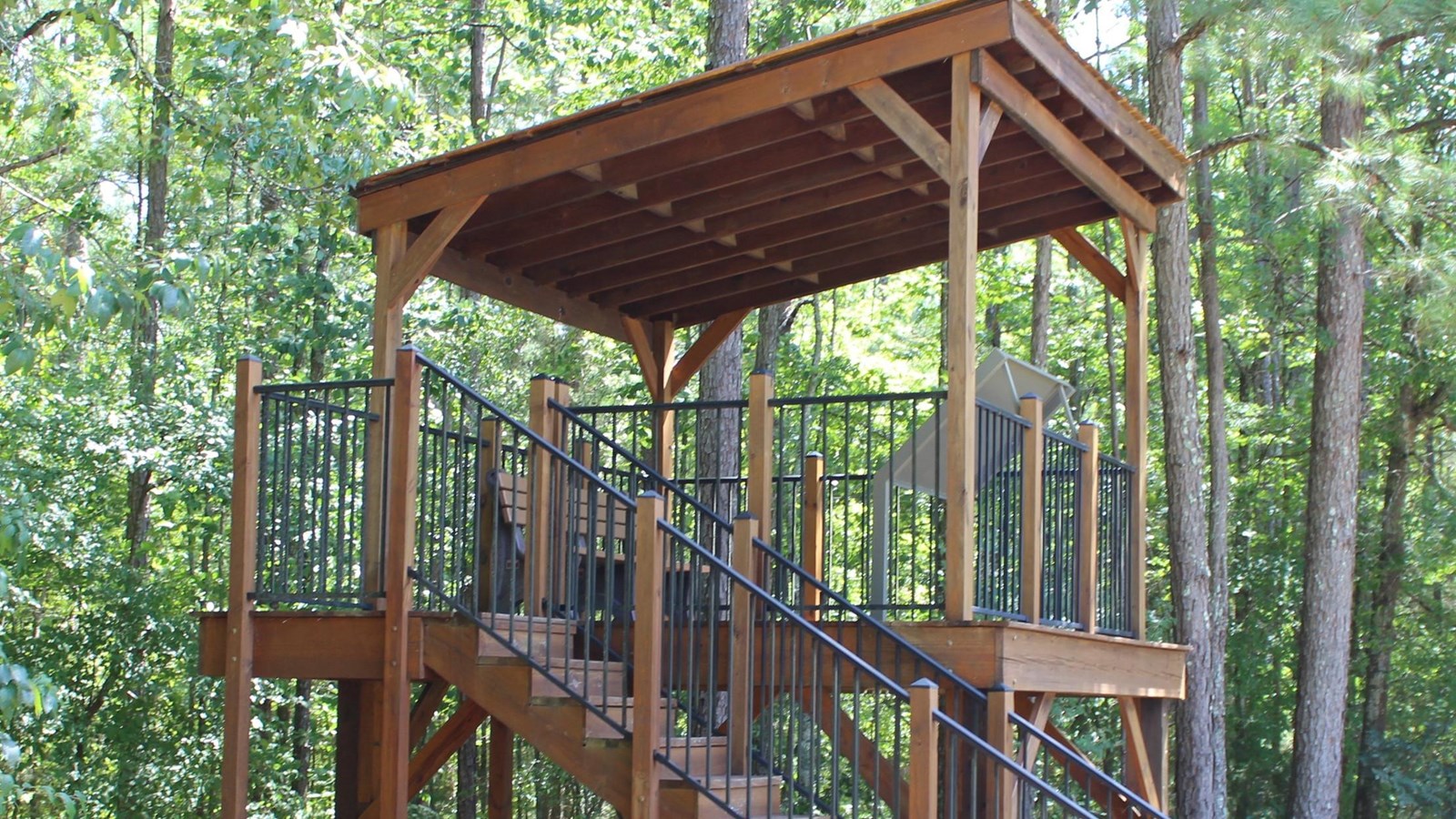 A wood platform with a staircase is located in the woods.
