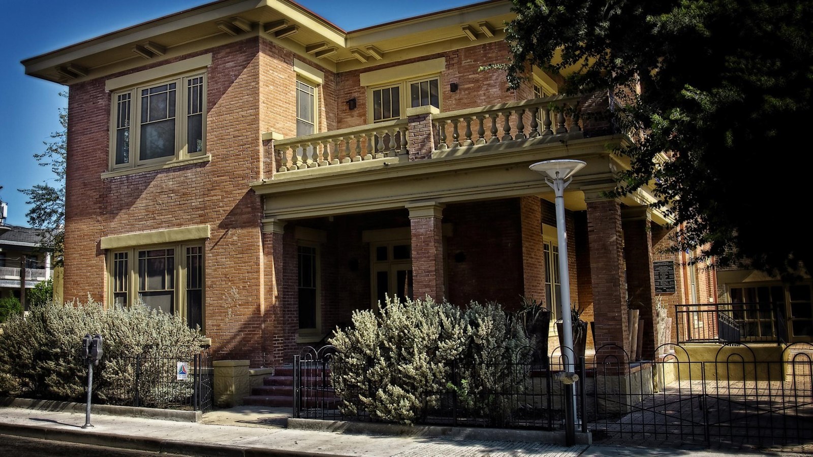 A two-story, red brick building with a covered porch and railed balcony.
