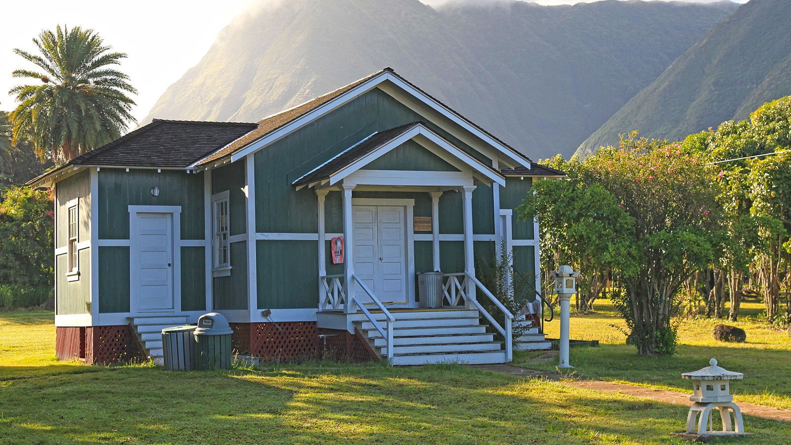 A teal building with white framing, white doors and a dark grey roof. 