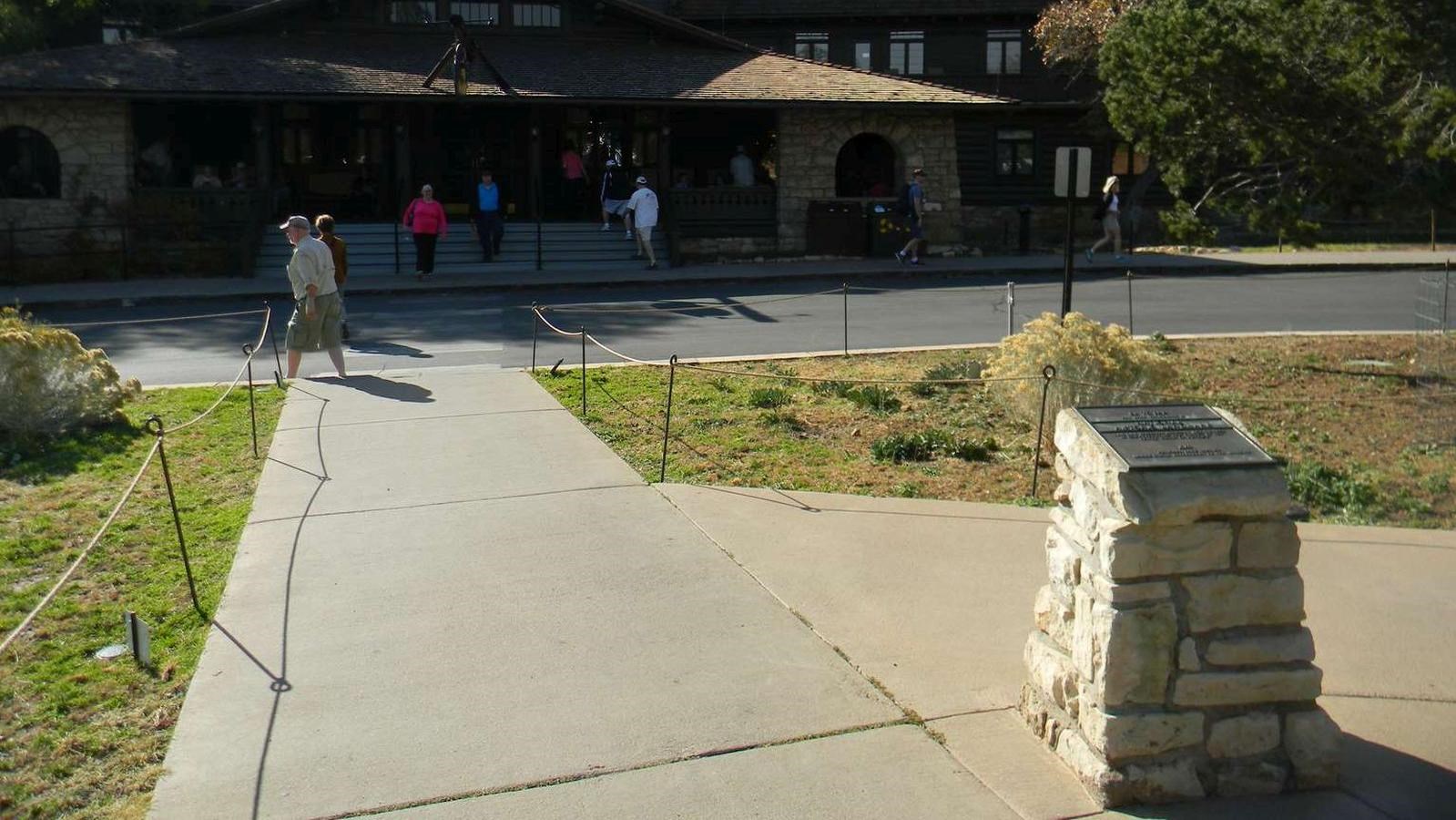 A waist-high stone pedestal with a bronze plaque on the top commemorates the El Tovar Hotel.