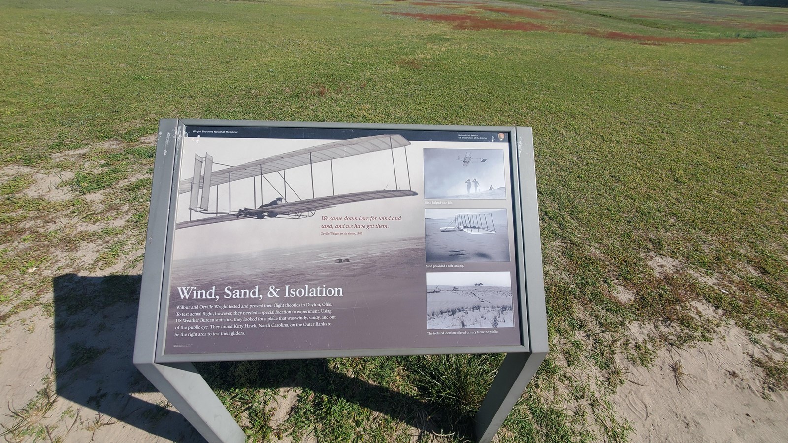Colored photograph of the wayside outside. Behind it is a flat, green, grass covered area.