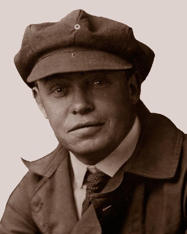 sepia portrait of a man in a coat and tie wearing a tweed cap