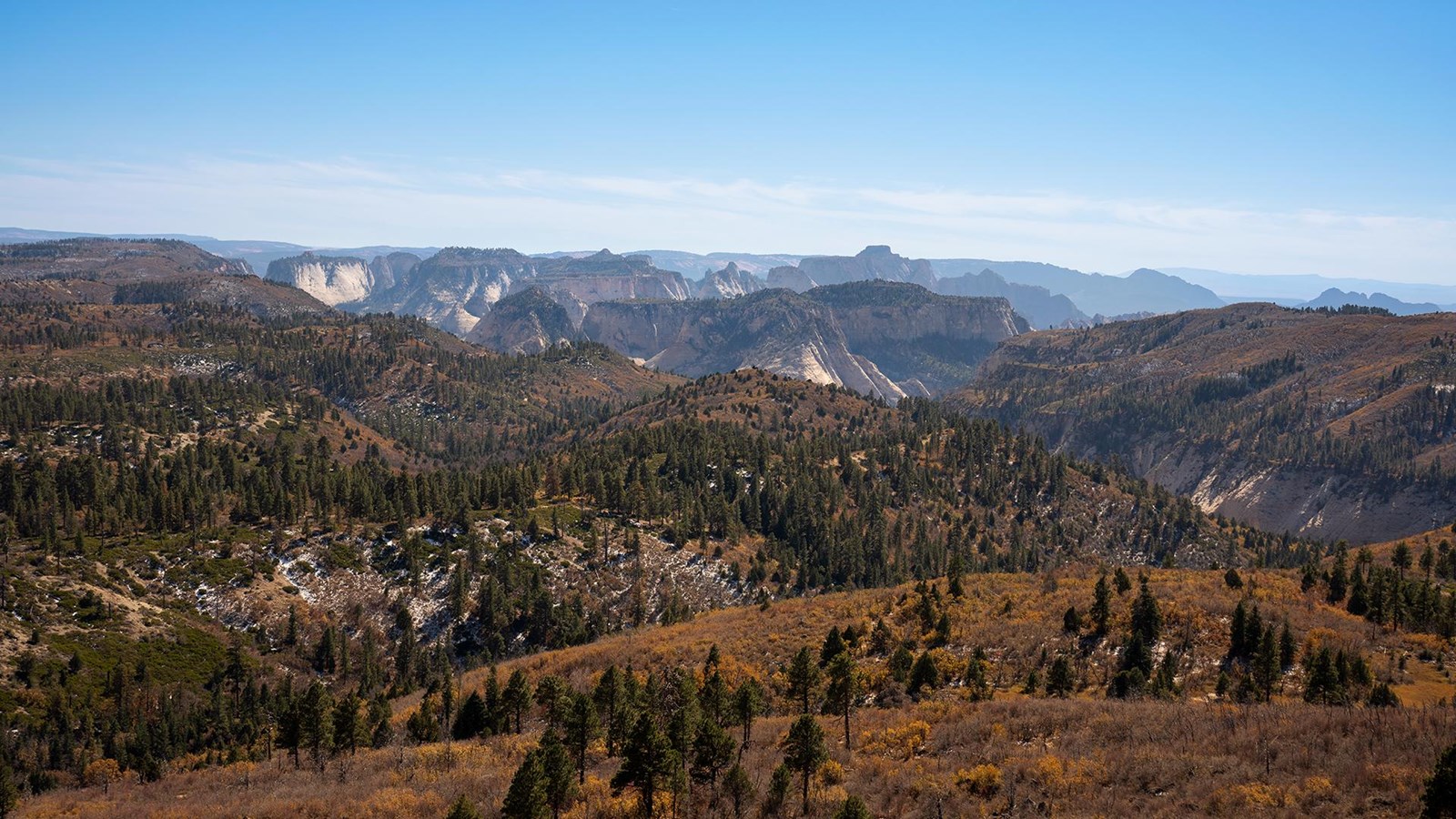 Photo of a wide landscape, overlooking mountain peaks and forests.