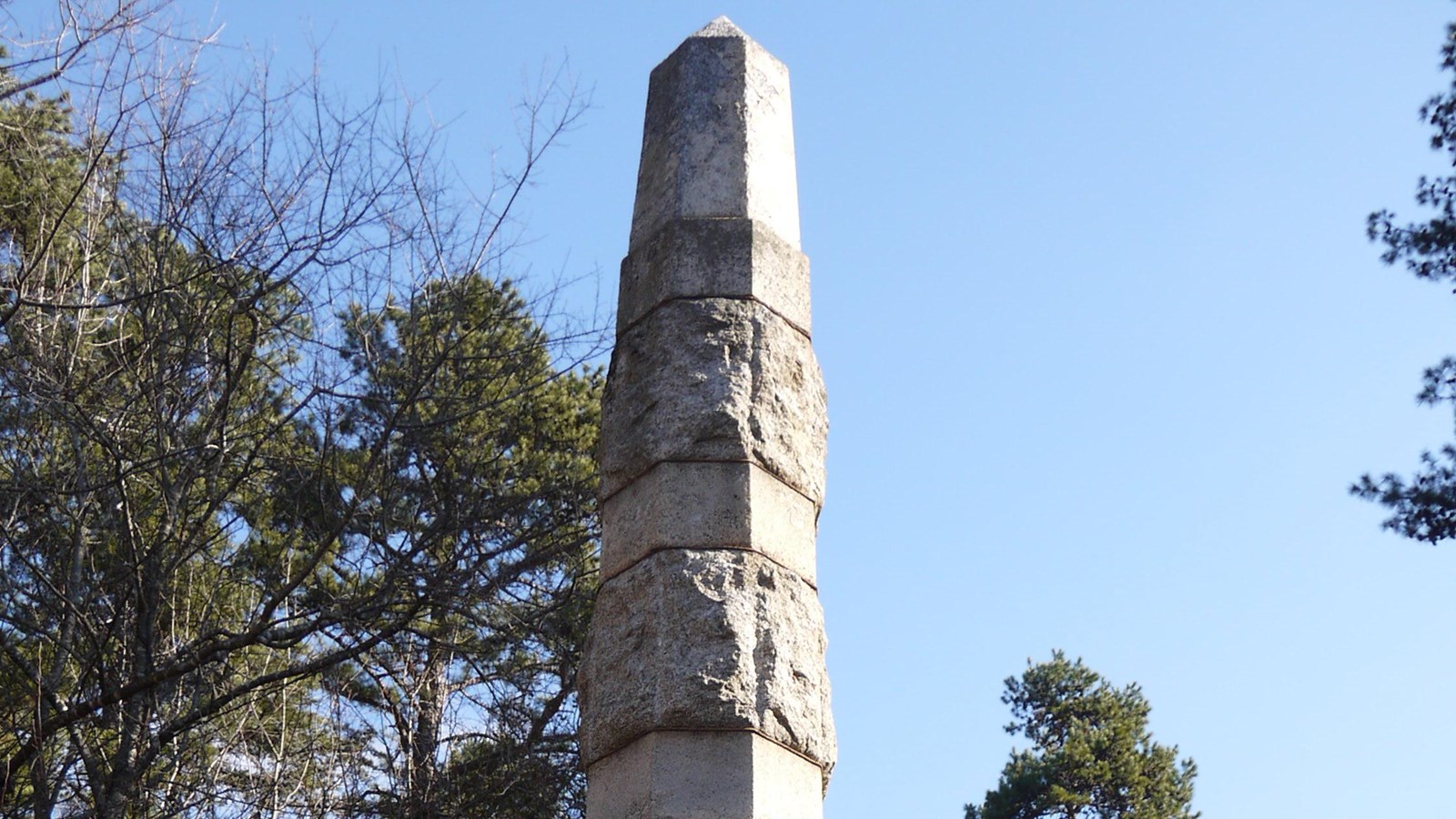 Tall obelisk made of stacked stone sections. Plaques at waist height explain the monument.