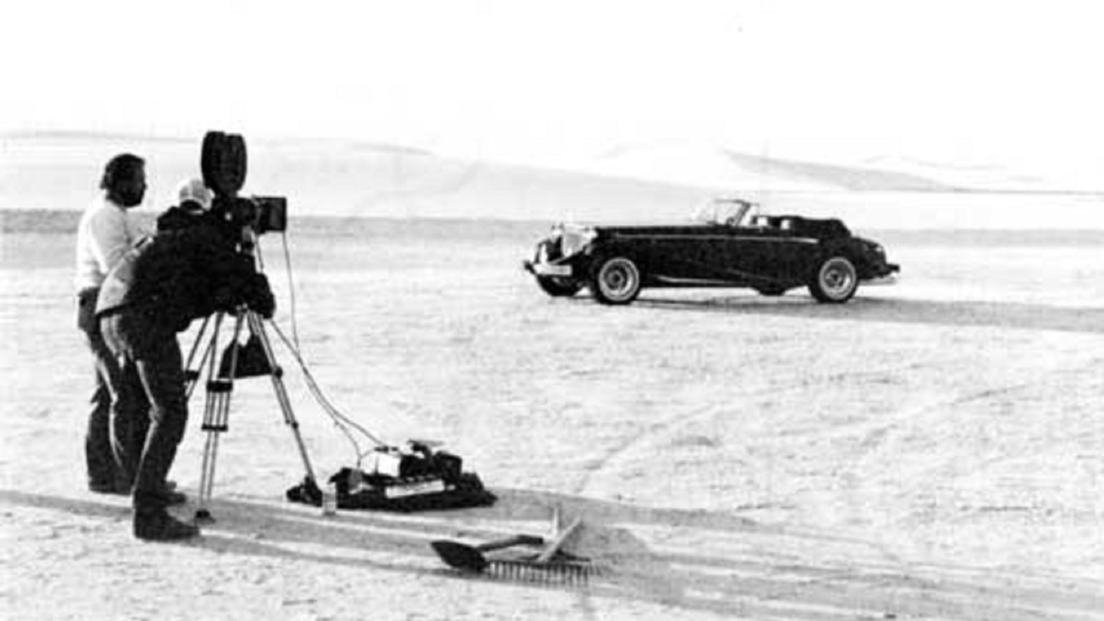 Cinematographers film a mid-1900s vehicle in the dunefield.