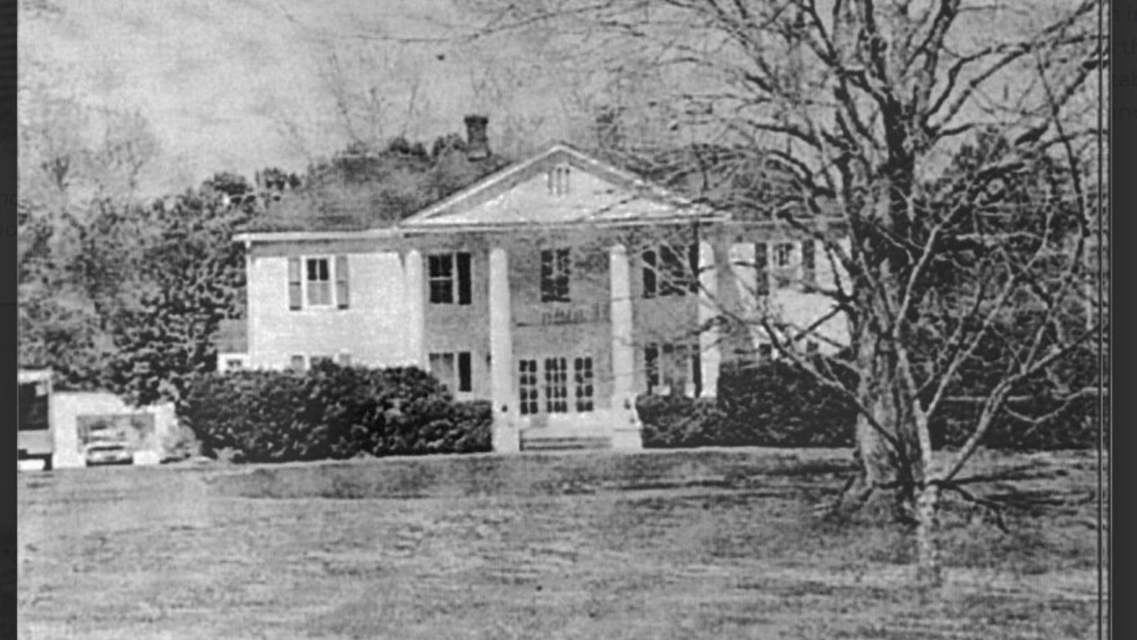 A historic image of a two-story white colonial revival home, with tall columns.