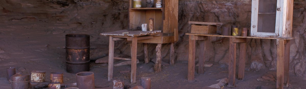 wooden tables with rusty cans beneath a rock alcove