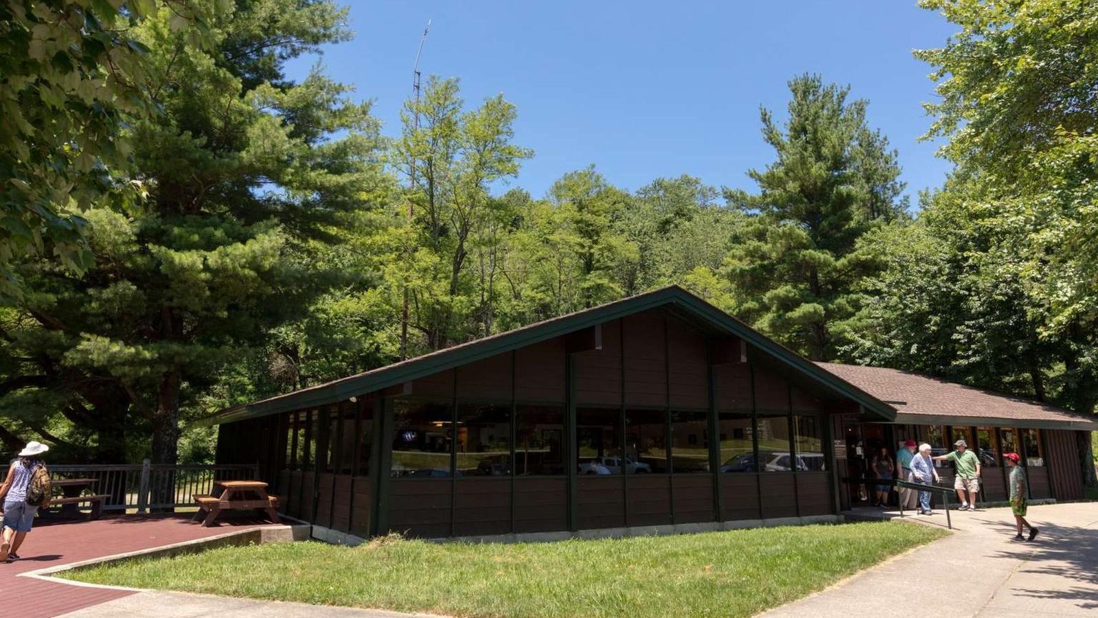 A rustic dark brown wood-sided building with dark green trim. 