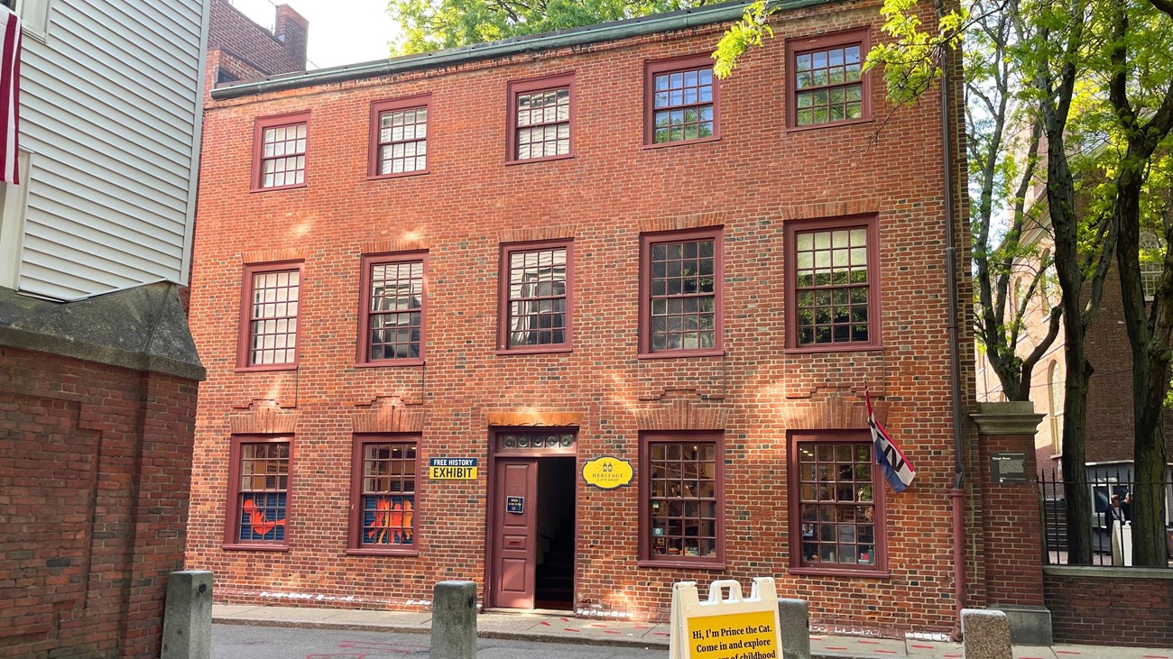 A three-story brick building with three rows of five paned glass windows.