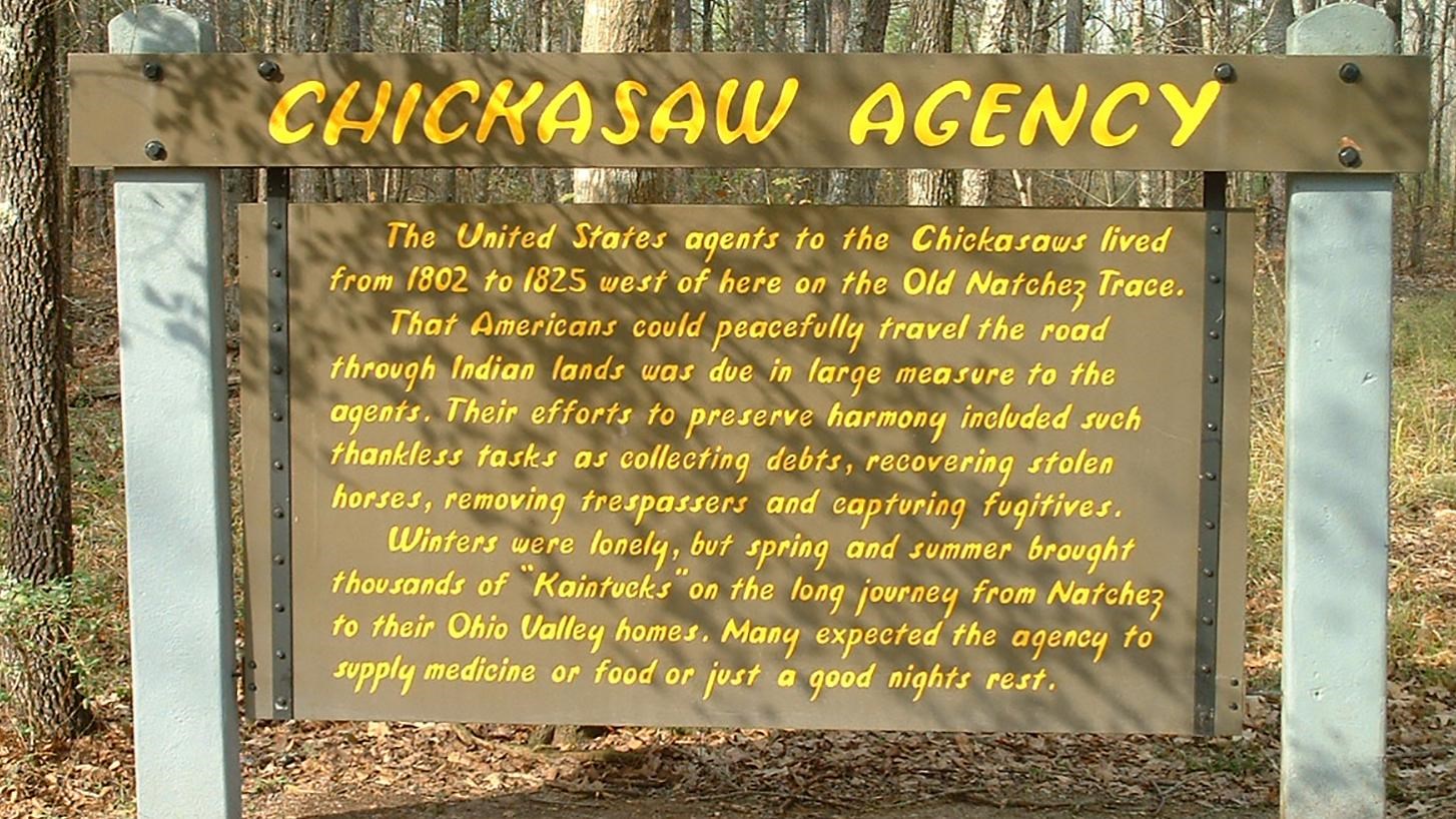 Brown wooden sign with yellow letters entitled