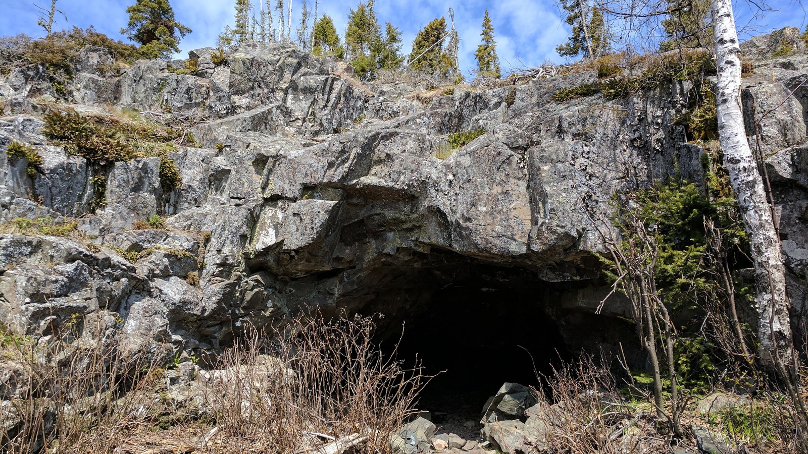 View of rocky outcropping with a dark cave. 