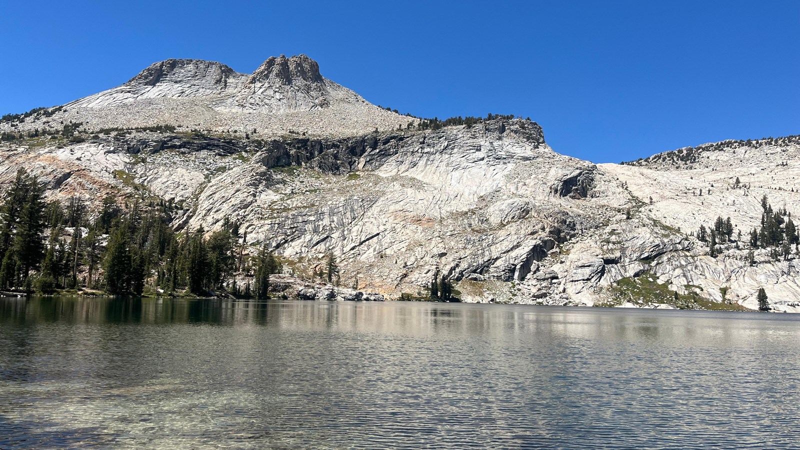 A blue alpine lake below a granite peak