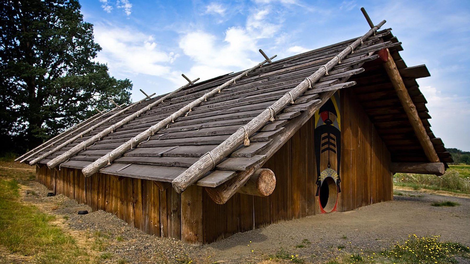 Wooden structure with pitched roof and walls going into the earth. Circular opening in front with pa