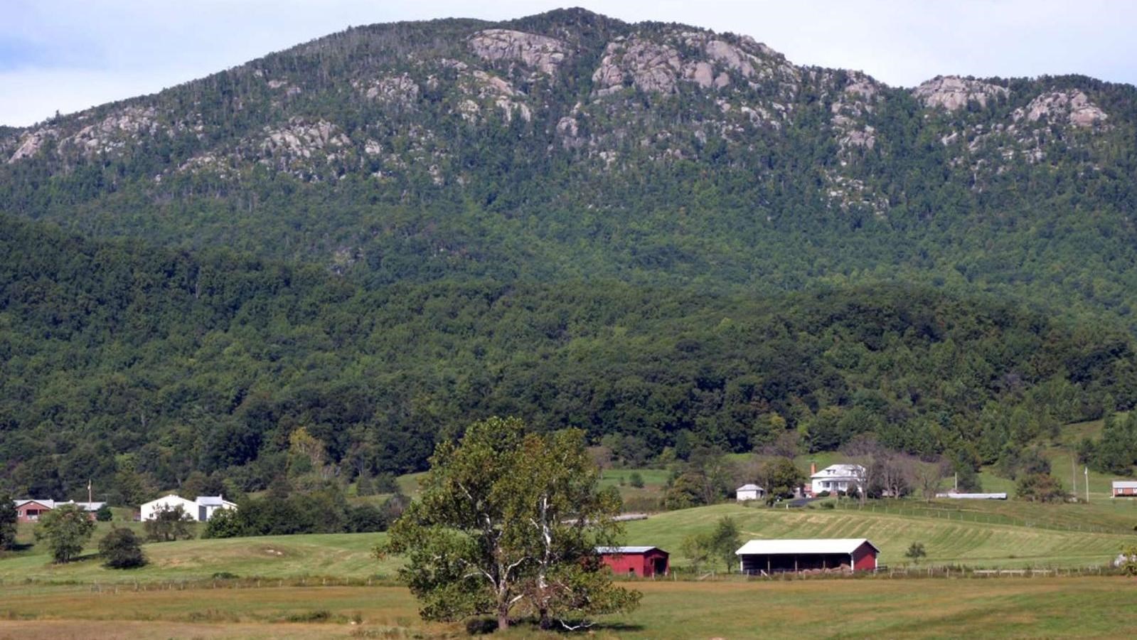 A color photograph of a rocky peak rising above pastoral farmland.