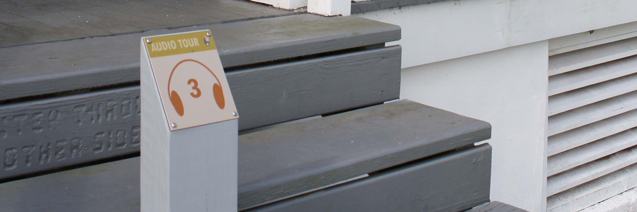a sign on blue stairs reads 3 and has headphones