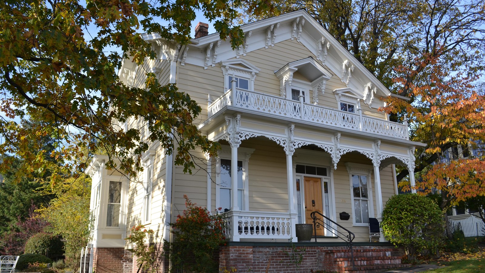 Yellow house with ornate porch. 