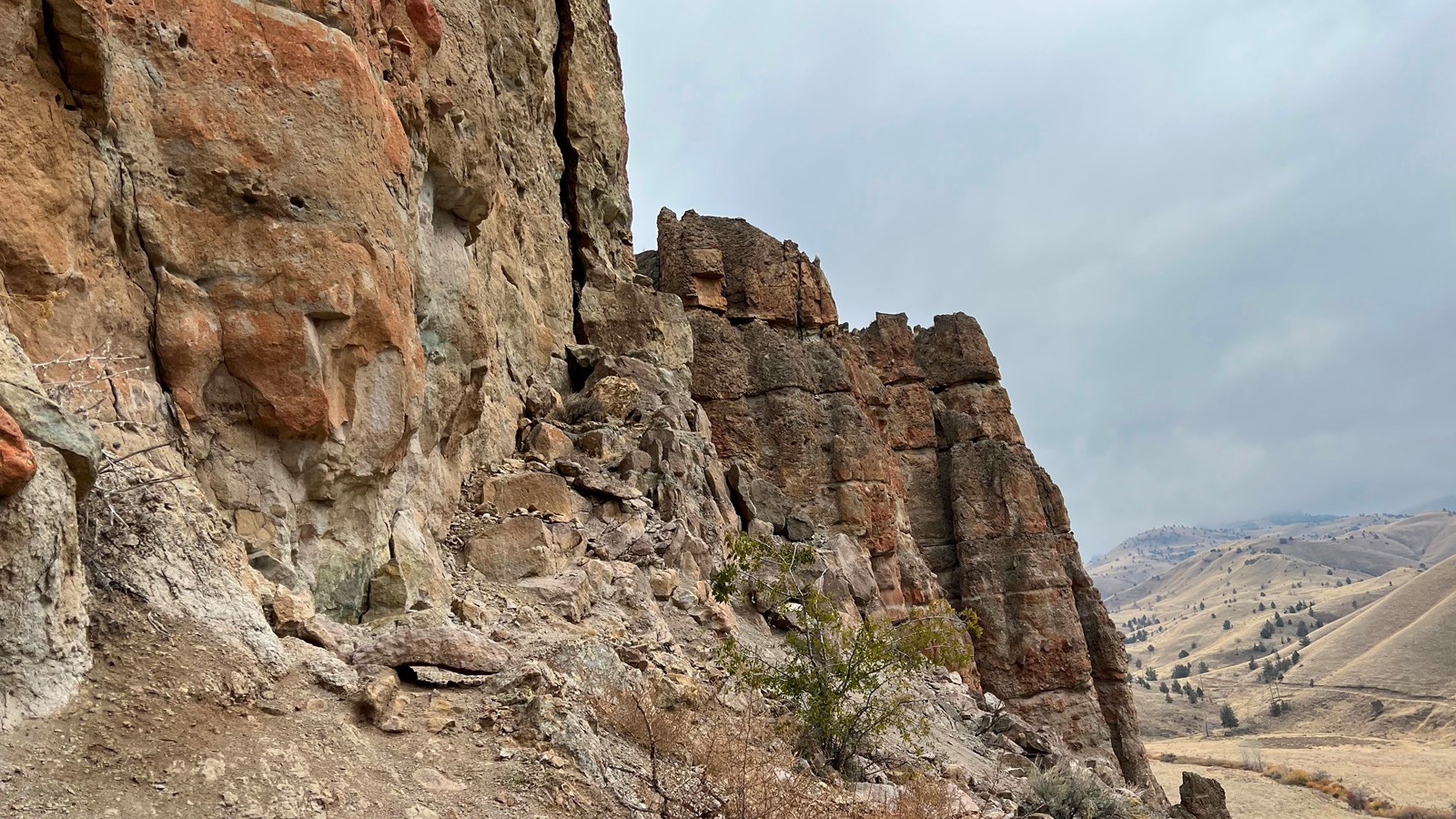 A view of layered mudflow cliff formations above a valley.
