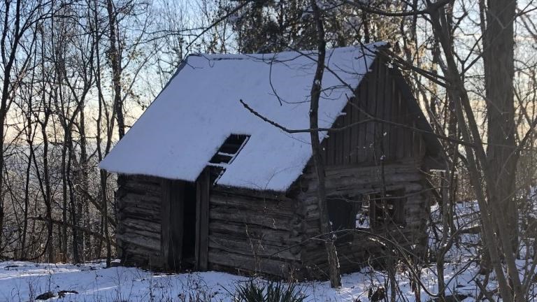 A two story cabin with a snow covered roof. 