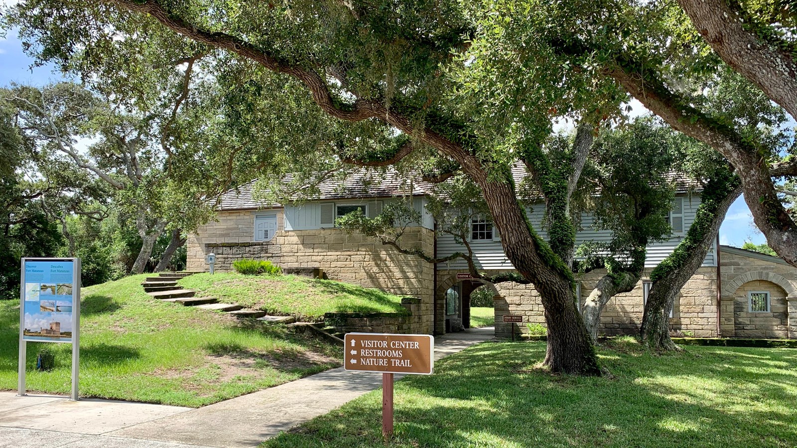 The front approach to the visitor center. large oak trees and coquina building