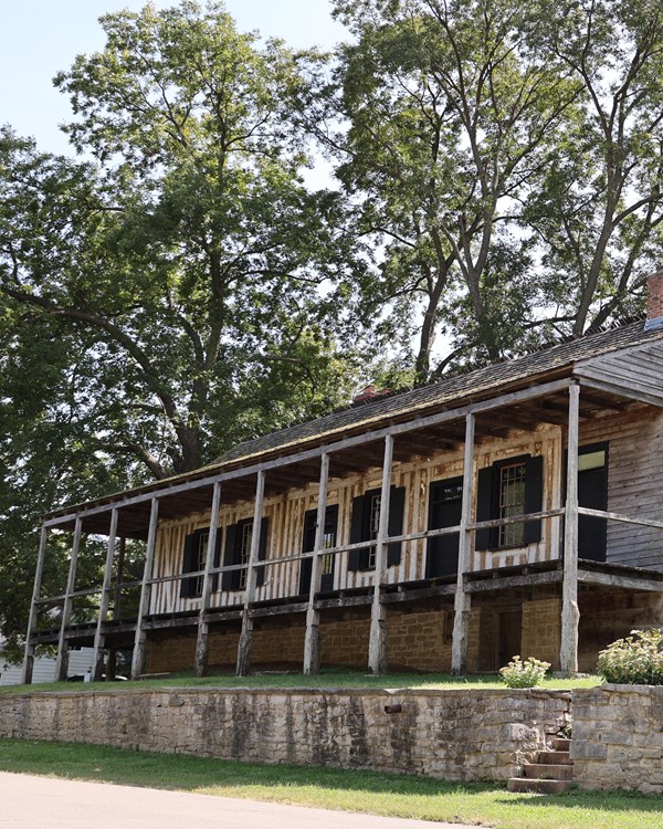 Large wooden building with a covered porch. Vertical log construction visible. 