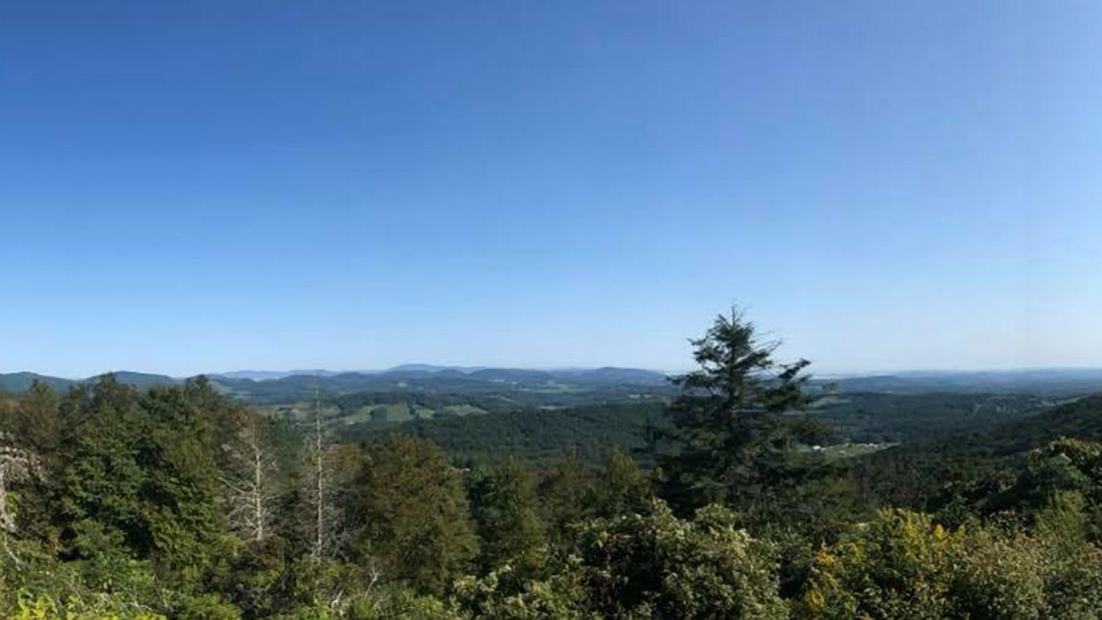 An open overlook with a valley below and mountain ridges in the distance