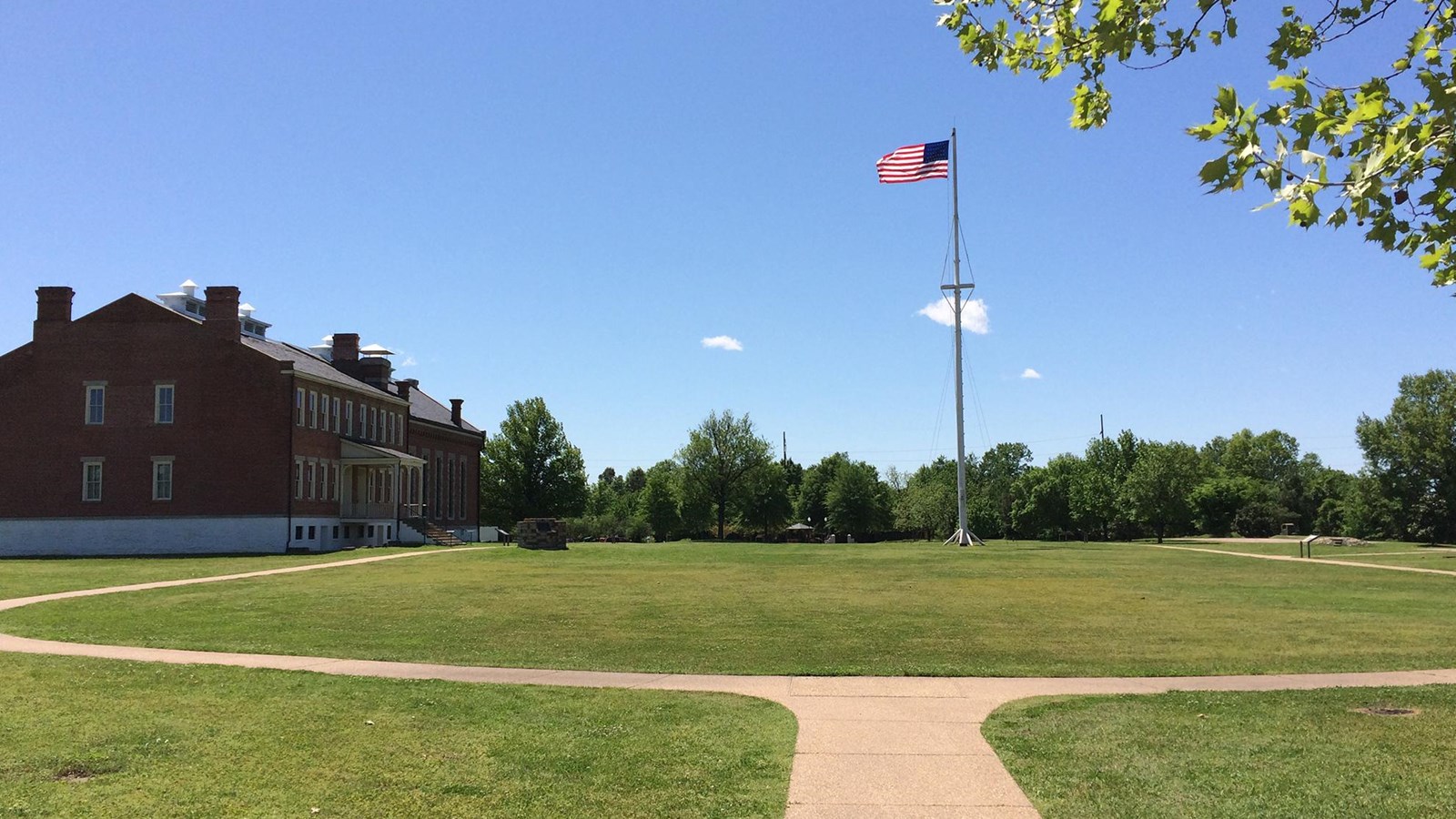 Football field size open field with green grass. Visitor center on left and tall flagpole on right.