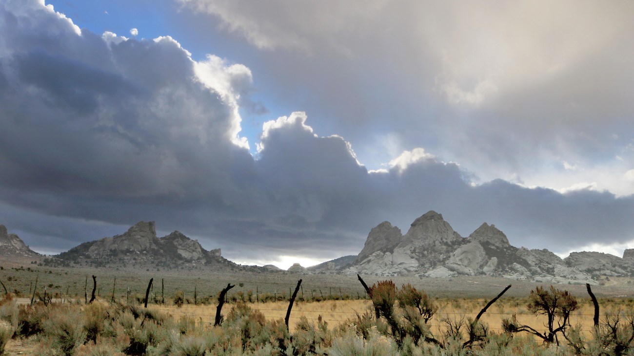Two rocky hills in the distance with a visible pass in between them. Spectacular cloudy sunset.