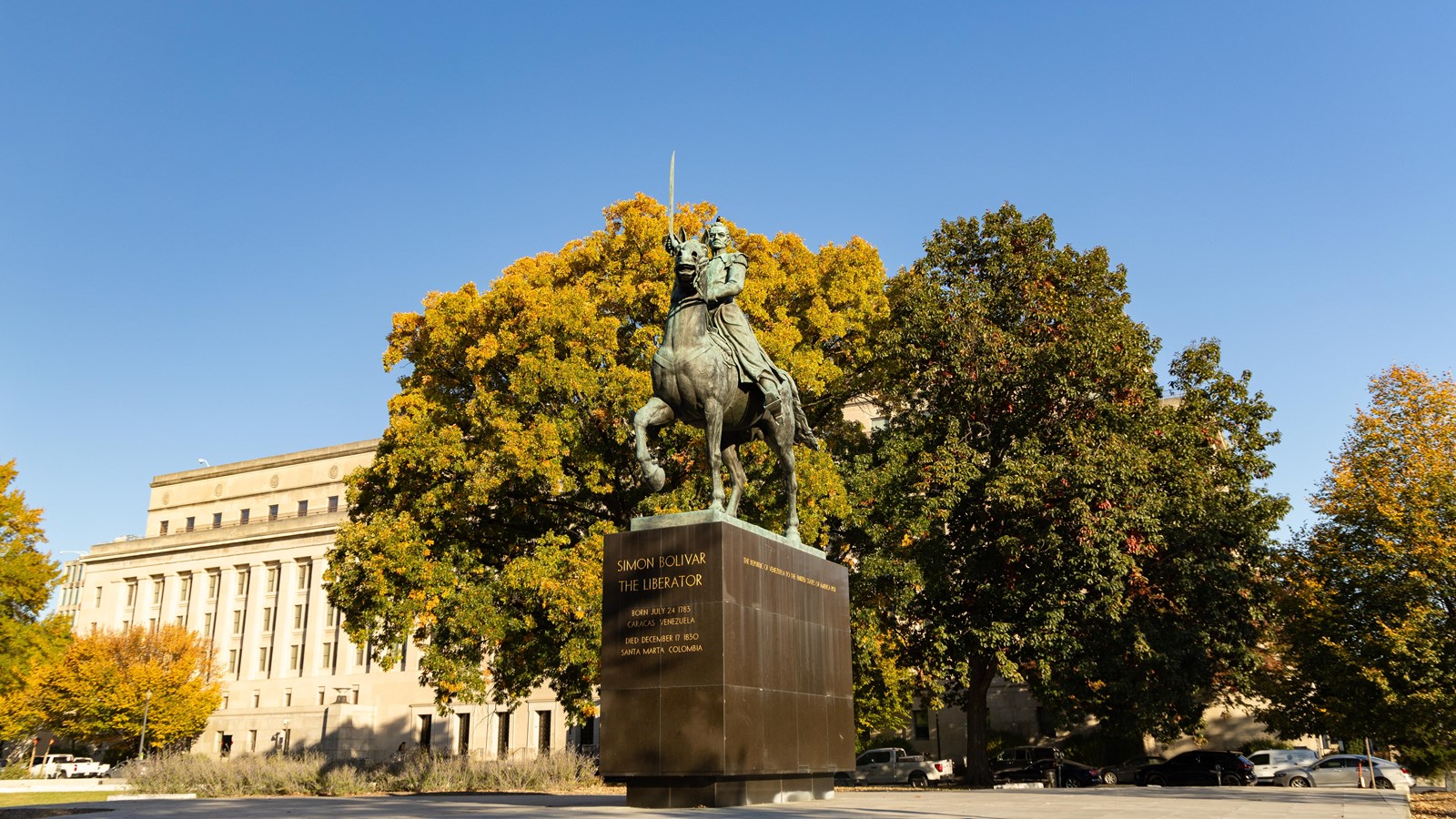 A large memorial of a man riding a horse with his sword raised high. Fall leaves fan out behind hime