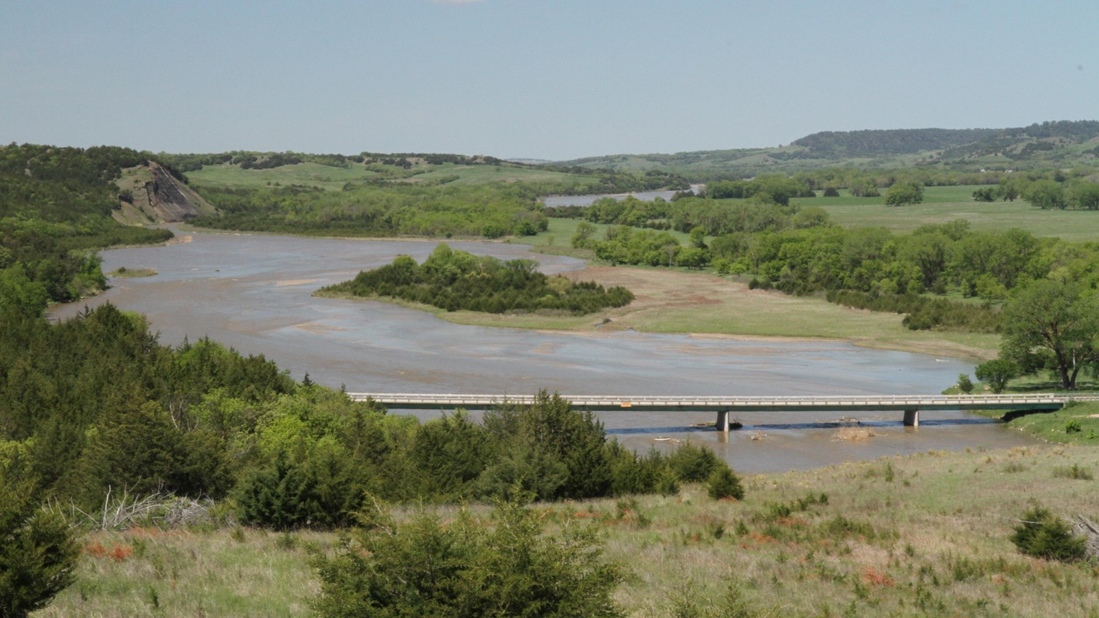 A bridge over a river with rolling hills and winding river going forward.