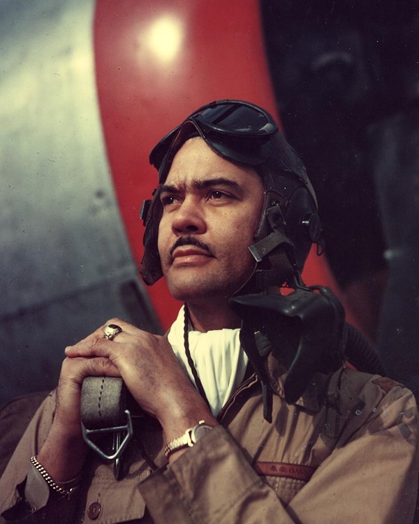 Color photograph of African American in military uniform standing in front of a plane.