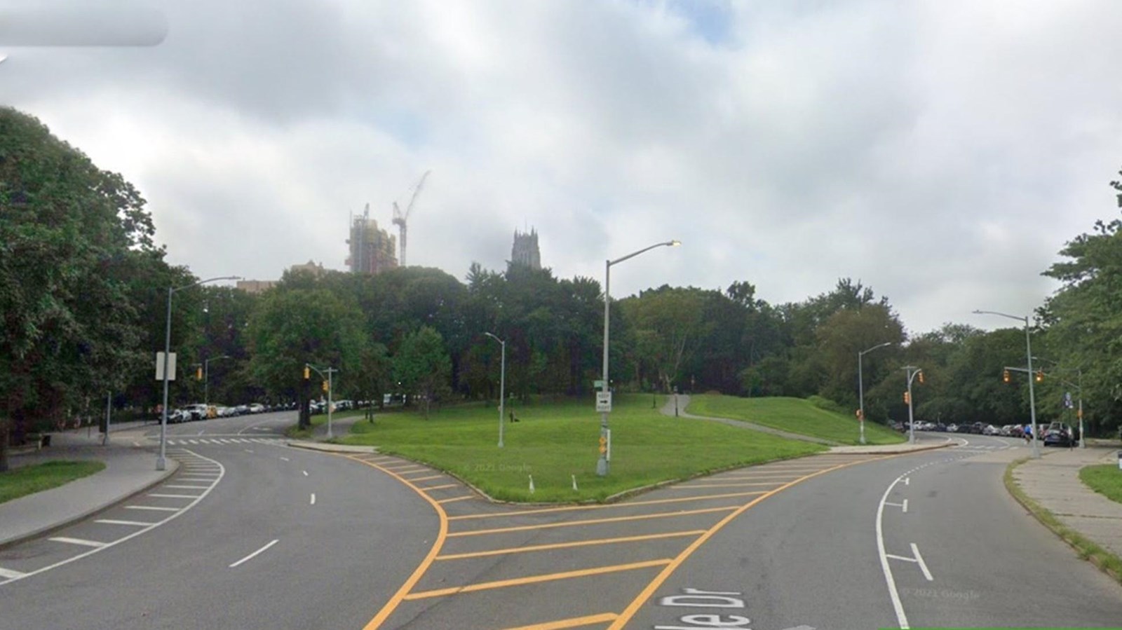 A fork in the road that splits into two two-lane roads with a grass island in the middle.