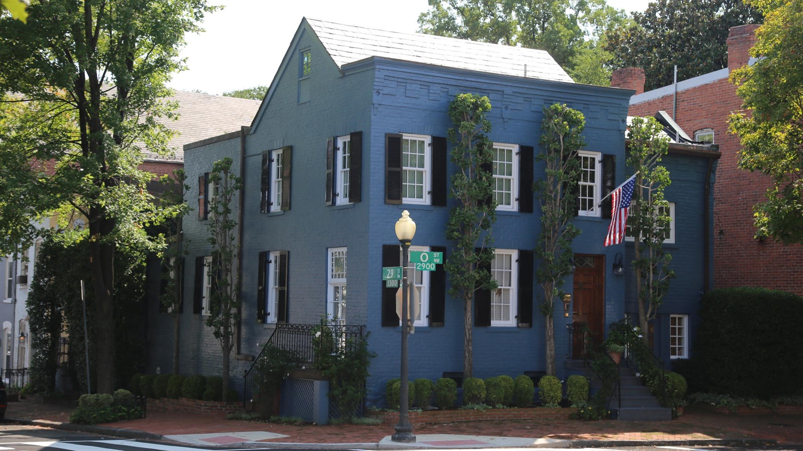 Two story brick house on a corner lot. The brick is painted blue.