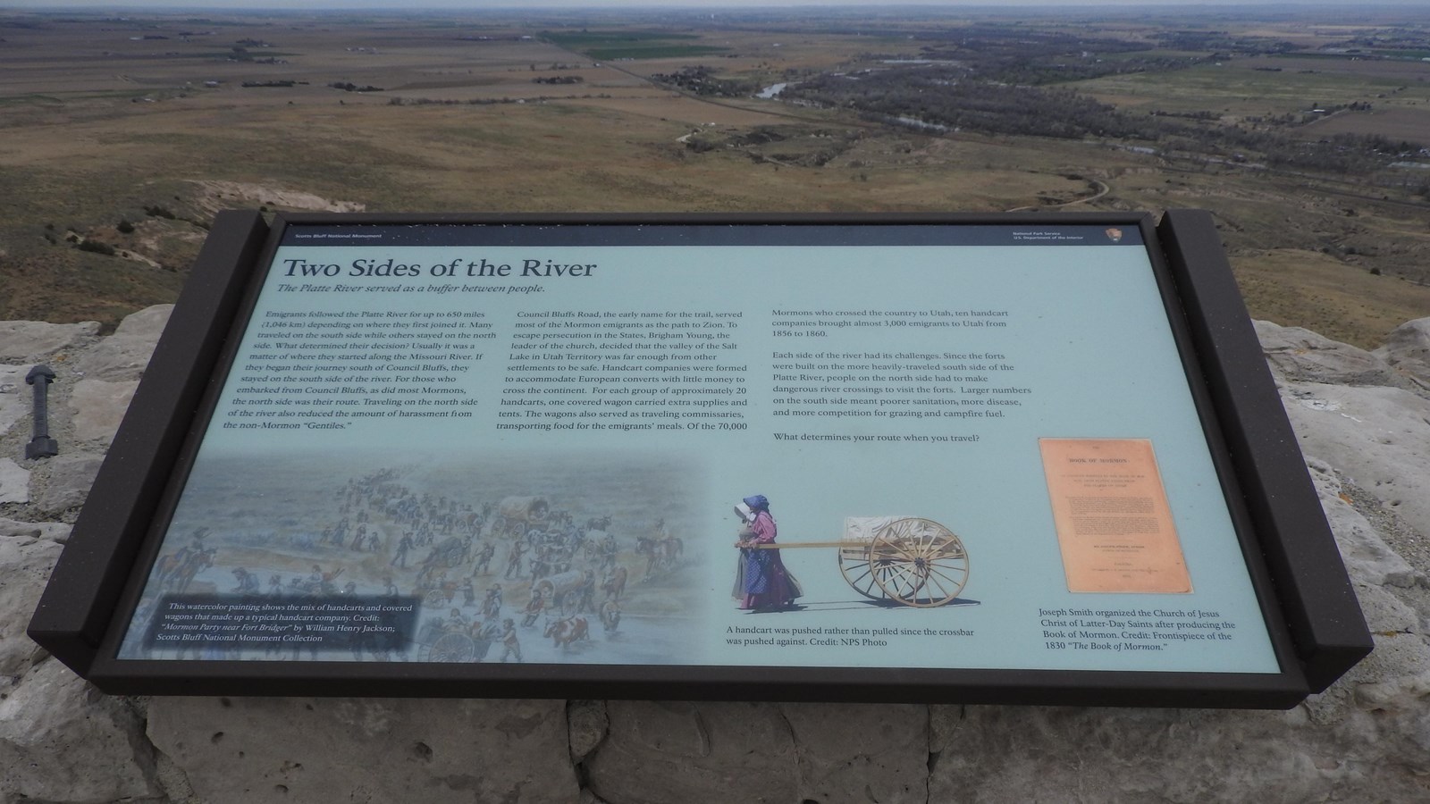 An interpretive wayside in a frame attached to a stone wall.